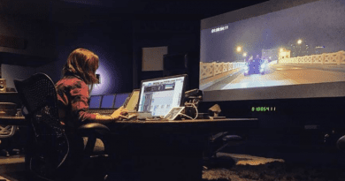 Paola Magrans trabajando en un moderno estudio de sonido frente a una pantalla de televisión gigante.